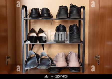 Ein Regal mit Schuhen im Schrank, Turnschuhe, Turnschuhe und Schuhe stehen im Regal im Flur, Damenschuhe, ein Paar alte Schuhe Stockfoto