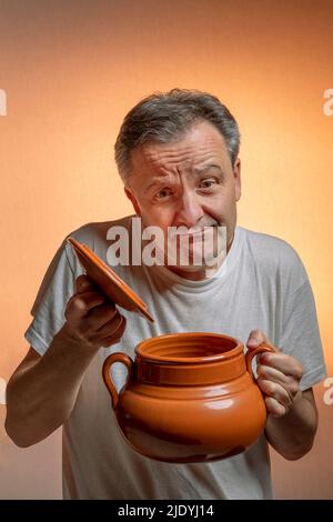 Ein Mann hält einen Tontopf in den Händen, der als Ausdruck der Enttäuschung gilt, weil er leer ist Stockfoto