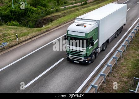 Großer LKW für die industrielle Langstrecken-Belieferung mit Sattelauflieger, der entlang der Autobahn vorrückt Stockfoto