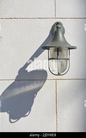 Abstraktes Bild mit einer wandmontierten Lampe, die einen Schatten auf das Mauerwerk wirft Stockfoto