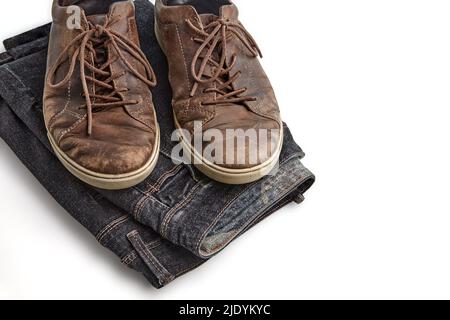 Stilvoll verzweifelte Vintage braune Lederschuhe und schwarze Jeans auf weißem Hintergrund isoliert. Lifestyle und Mode. Obere Aussicht mit Kopierbereich Stockfoto