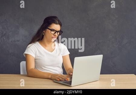 Unglückliche Frau arbeitet am Computer, der mit Geräteproblemen bedrängt ist Stockfoto