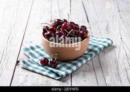 Frische Kirschen mit Wassertropfen in Holzschüssel auf Holztisch Stockfoto