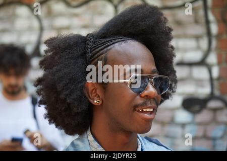 MAILAND, ITALIEN - 18. JUNI 2022: Mann mit Frisur mit Zopf und Sonnenbrille vor der Fendi Fashion Show, Mailand Fashion Week Street Style Stockfoto