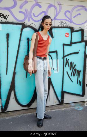 MAILAND, ITALIEN - 18. JUNI 2022: Mann mit orangefarbenem Tank-Top und Denim-Hose vor der Fendi-Modenschau im Street-Style der Milan Fashion Week Stockfoto