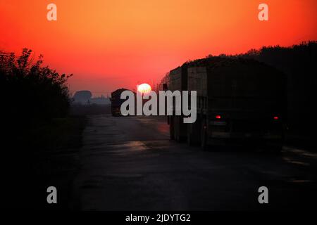 Bei Sonnenuntergang, zwei Lastwagen auf der Straße. Selektive Fokus Stockfoto