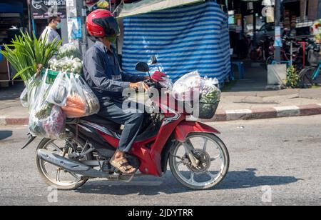 SAMUT PRAKAN, THAILAND, 19 2022. MÄRZ, Ein Mann fährt mit einem Motorrad auf der Straße und kauft in Plastiktüten Stockfoto