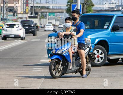 SAMUT PRAKAN, THAILAND, MÄRZ 19 2022, Ein Mann mit einem Jungen auf einem Motorrad steht an einer Kreuzung Stockfoto