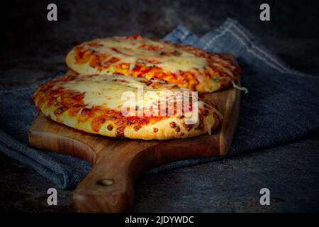 Gemüsepizza mit geschmolzenem Käse, gekocht auf einem Holzbrett. Mit einem Geschirrtuch auf einem grunge Hintergrund. Stockfoto