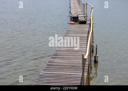 Schmale Holzbrücke mit einer Planke in der Mitte Stockfoto