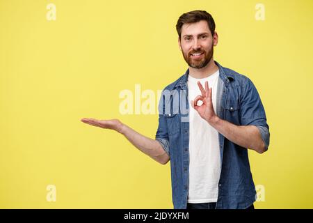 Positiver Mann zeigt seine Hand an leerer Stelle zur Seite und zeigt Zeichen okey Stockfoto