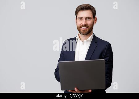 Erfolgreicher Geschäftsmann in Anzug mit Laptop auf grauem Hintergrund Stockfoto