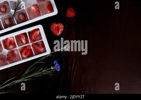 Erdbeereis in den Formen. Sommereis für Cocktails, Eis und Desserts vorbereiten. Speicherplatz kopieren. Stockfoto