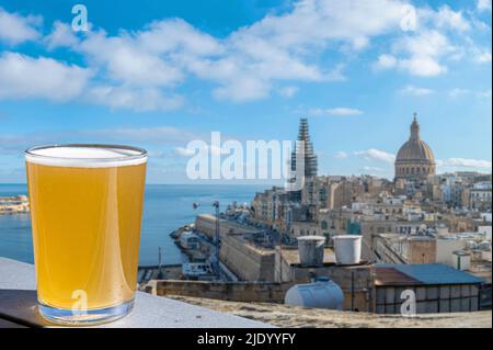 Ein Glas Bier mit Blick auf die Altstadt von Valletta und den Hafen in Valletta, Malta. Stockfoto