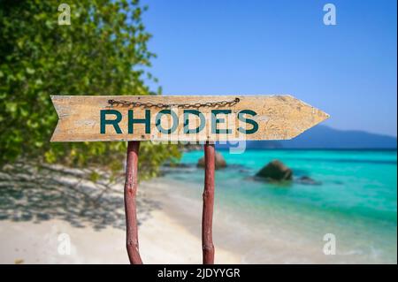 Rhodes Holzpfeil Straßenschild gegen Strand mit weißem Sand und türkisfarbenem Wasser Hintergrund. Reise nach Griechenland Konzept. Stockfoto