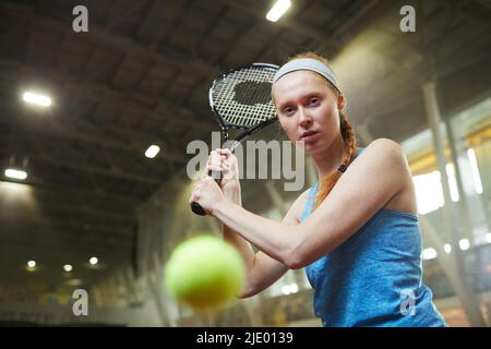 Porträt einer ernsthaften Rothaarige Tennisspielerin in Sportstirnband konzentriert sich auf die Bewegung des Balls schlagen Tennisball auf dem Platz Stockfoto