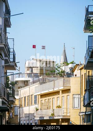 Wohnviertel in Süd-Nikosia mit zwei türkischen und TRNC-Flaggen von der anderen Seite, die auf einem Gebäude stehen Stockfoto