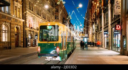 Helsinki, Finnland. Die Straßenbahn fährt von der Haltestelle Aleksanterinkatu Straße. Nacht Abend Weihnachten neues Jahr festliche Beleuchtung auf der Straße. Schöne Stockfoto