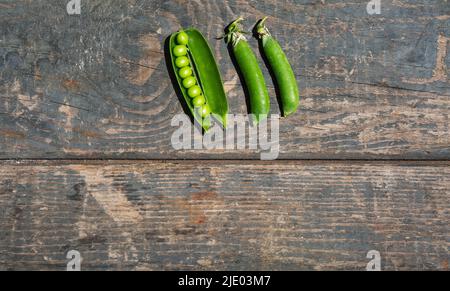 Grüne Erbsenstiele auf einer Holzstruktur. Platinen. Kochen, Gartenarbeit, Gemüsegarten Stockfoto