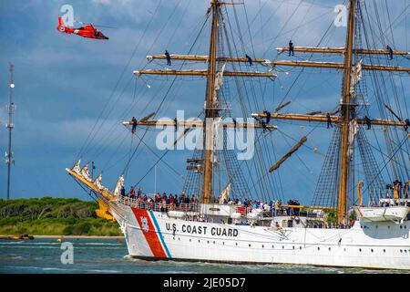 Galveston, Texas, USA. 10.. Juni 2022. Ein Helikopter der Küstenwache Houston MH-65 Dolphin fliegt über den US-Küstenwächter-Cutter Barque Eagle, der den Galveston-Kanal in Richtung Pier 21 in Galveston, Texas, durchfährt, 10. Juni 2022. Der Eagle, der an der Coast Guard Academy in New London, Connecticut, untergebracht ist, wird als Trainingsplattform für zukünftige Küstenwache-Offiziere genutzt und besuchte Galveston, Texas, zum ersten Mal seit 1972. Quelle: U.S. Coast Guard/ZUMA Press Wire Service/ZUMAPRESS.com/Alamy Live News Stockfoto