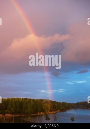 Landschaft mit großem Regenbogen am Himmel bei Sonnenuntergang Stockfoto