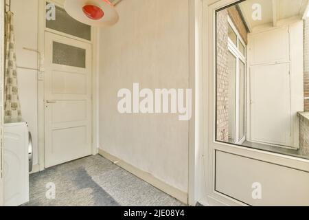 Ein geräumiges, helles und leeres Zimmer mit einem Kleiderschrank und einer Waschmaschine, in einem minimalistischen Stil Stockfoto