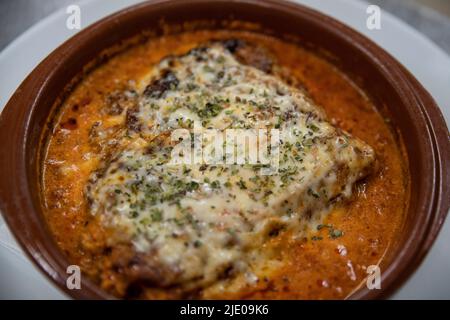 Hausgemachte Lasagne in einem runden Terrakotta-Topf gebacken, individuelle Portion des traditionellen italienischen Gerichts aus Lasagne-Nudelschichten Stockfoto