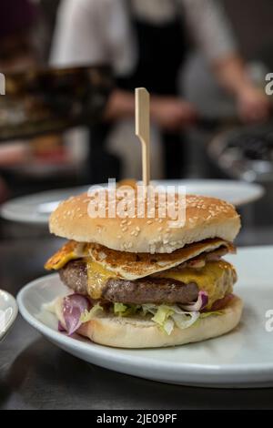 Die Restaurantküche ist mit einem frisch zubereiteten Cheeseburger mit geröstetem Sesambrötchen, frischem Gemüse, Rinderburger, geschmolzenem Käse und Spiegelei ausgestattet Stockfoto
