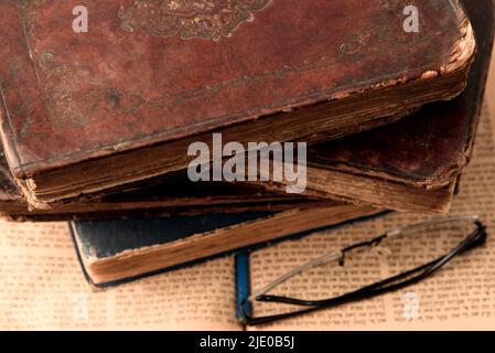 Alte abgenutzte, schäbige jüdische Bücher mit Lederbindung auf offener, verschwommener Tora im Hintergrund. Nahaufnahme. Selektiver Fokus Stockfoto