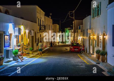 Architektonische Gebäude mit Menschen, die in den Straßen des Dorfes Chora in der Nacht zu Fuß. Stadtfotografie des malerischen Dorfes Chora in Kythera ist Stockfoto