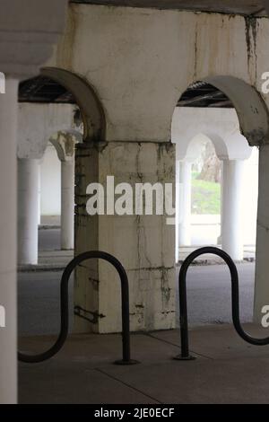 Eine Kolonnade aus Säulen in der Innenstadt, die eine Brücke über dem Hotel hält. Stockfoto