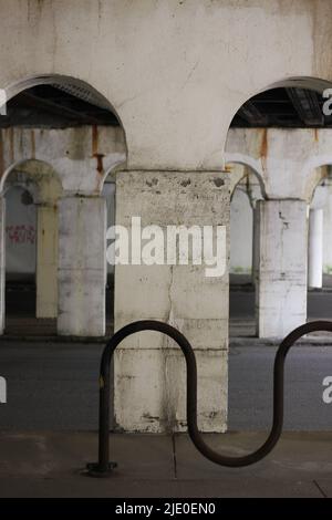 Eine Kolonnade aus Säulen in der Innenstadt, die eine Brücke über dem Hotel hält. Stockfoto