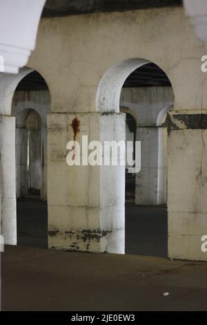 Eine Kolonnade aus Säulen in der Innenstadt, die eine Brücke über dem Hotel hält. Stockfoto