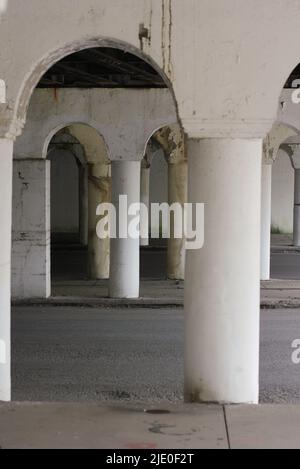 Eine Kolonnade aus Säulen in der Innenstadt, die eine Brücke über dem Hotel hält. Stockfoto