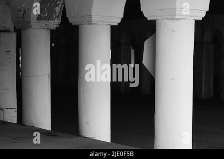 Eine Kolonnade aus Säulen in der Innenstadt, die eine Brücke in Schwarz und Weiß über sich hält. Stockfoto