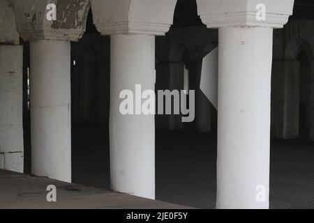 Eine Kolonnade aus Säulen in der Innenstadt, die eine Brücke über dem Hotel hält. Stockfoto