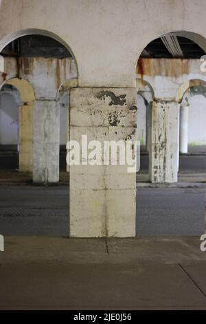 Eine Kolonnade aus Säulen in der Innenstadt, die eine Brücke in Schwarz und Weiß über sich hält. Stockfoto