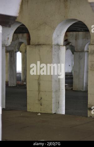 Eine Kolonnade aus Säulen in der Innenstadt, die eine Brücke in Schwarz und Weiß über sich hält. Stockfoto