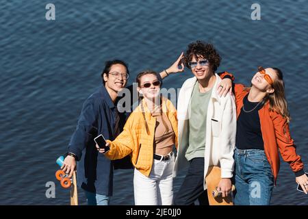 Glücklicher asiatischer Mann mit Siegeszeichen in der Nähe von stilvollen multiethnischen Freunden Stockfoto