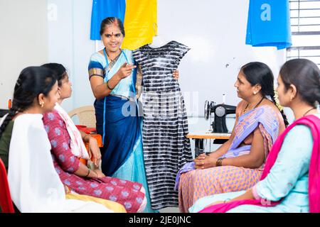 Frau, die Studenten im Schneiderschulungszentrum Stoffdesign unterrichtet - Konzept des Lernens, der Beschäftigung und der Werkstatt. Stockfoto