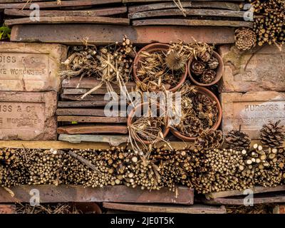 Das Bug Hotel besteht aus gestapelten Ziegeln, Dachziegeln, Pflanzentöpfen und Zweigen in einem britischen Garten. Stockfoto