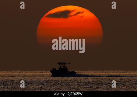 Ein Einzelboot fährt unter der untergehenden Sonne in den Florida Keys (Marathon, FL). Stockfoto