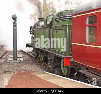 Ein historischer Dampfzug, der vom Bahnhof wegfährt. Stockfoto