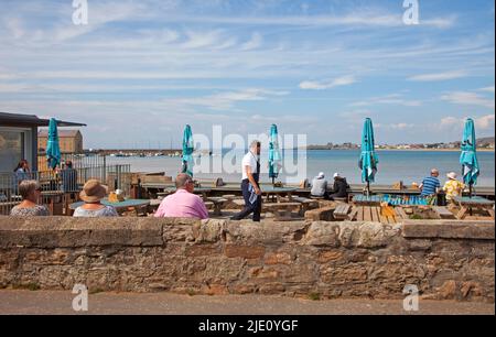 Elie, Fife, Schottland, Großbritannien. 24.06.2022. Heiß in der ruhigen Hafenstadt East Neuk an der Fife Coast. Temperatur 20 Grad am frühen Morgen für diejenigen, die das Glück haben, die Freizeit zu haben, um es zu genießen. Im Bild: Gäste entspannen sich im Beach Cafe. Quelle: Arch White/alamy Live News. Stockfoto