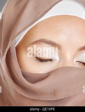 Bescheidene arabische Frau, die Make-up trägt und das Gesicht mit einem braunen traditionellen Hijab bedeckt ist. Nahaufnahme einer schönen jungen muslimischen Frau mit strahlender Haut und Stockfoto