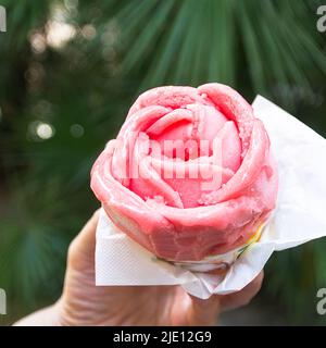 Erdbeereis in Form einer Blume, die von einer jungen Frau gehalten wird Stockfoto