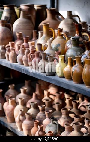 Viele einzigartige handgemachte bunte Tonkannen und Vasen in verschiedenen Formen im Regal auf dem lokalen Markt Stockfoto