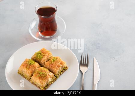 Pistazien-Baklava auf einem weißen Teller mit türkischem Tee Stockfoto