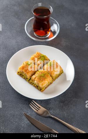 Traditionelle Pistazien-Baklava mit türkischem Tee.Ein Teller Baklava auf dunklem Hintergrund Stockfoto