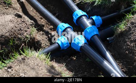 PVC-Pipeline im Garten und schwarze Rohre im Boden Stockfoto